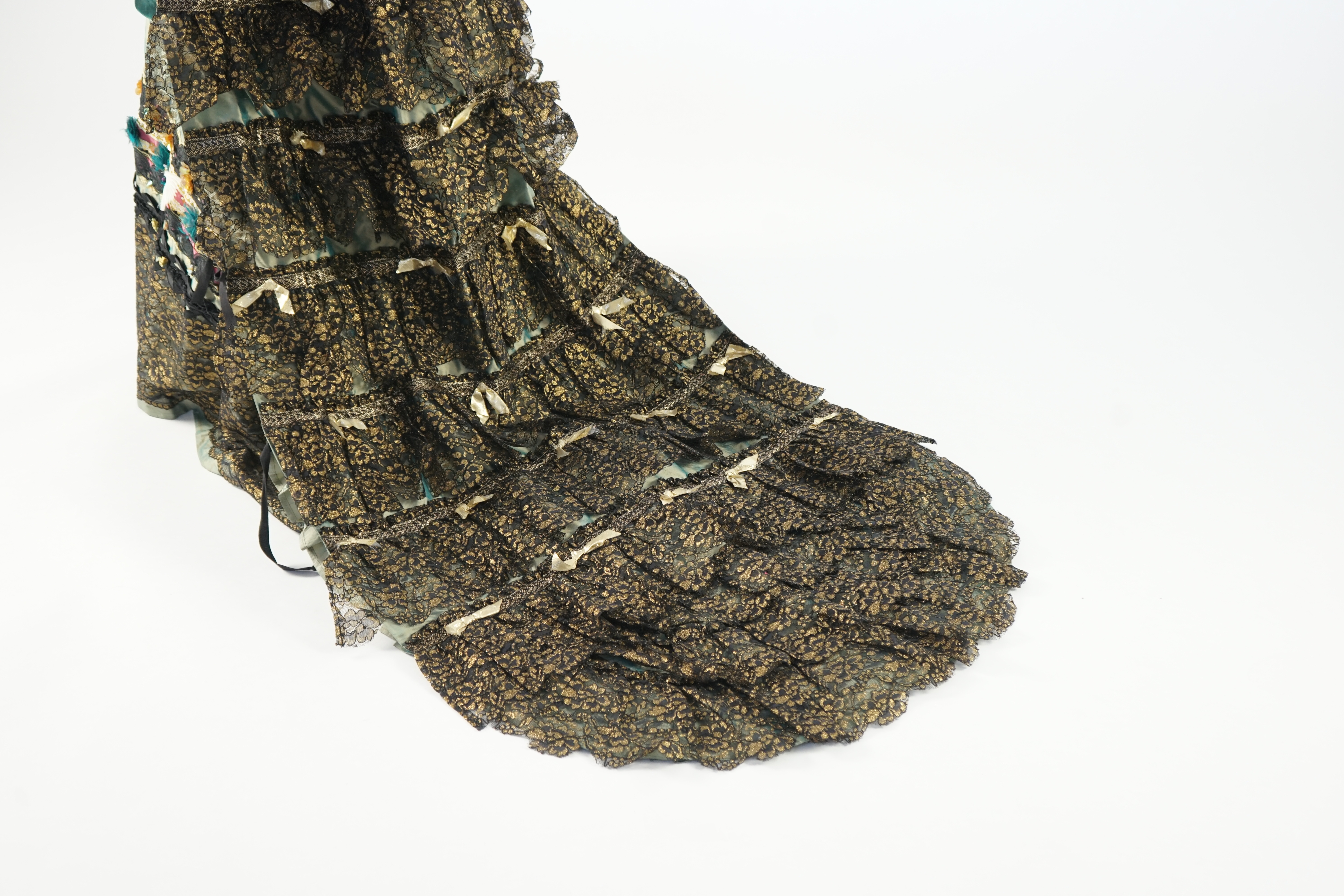 An Edwardian style lady's green taffeta skirt decorated with beaded, sequinned, ribboned border and swags of silk velvet, together with matching train layered with frilled black and gold lace, appliquéd with gold bows